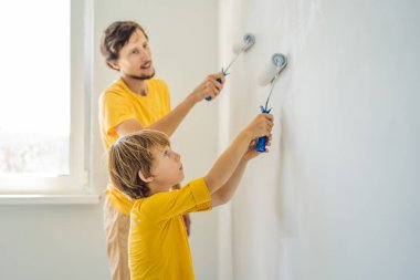 Baba ve oğul evlerinde duvar boyuyor. Taşınırken yapıyorlar.