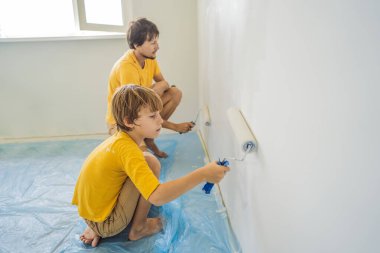 Baba ve oğul evlerinde duvar boyuyor. Taşınırken yapıyorlar.