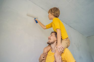 Baba ve oğul evlerinde duvar boyuyor. Taşınırken yapıyorlar.