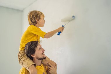 Baba ve oğul evlerinde duvar boyuyor. Taşınırken yapıyorlar.