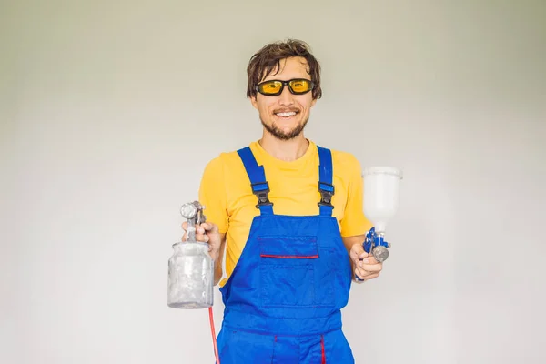 Pintor em roupas de trabalho com uma pistola de pintura — Fotografia de Stock