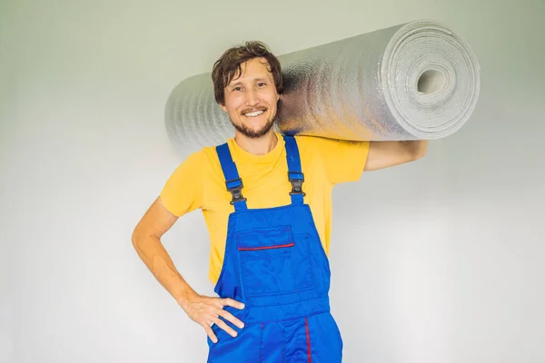 Homem segurando um rolo de pano isolante para instalar um piso de madeira laminado — Fotografia de Stock