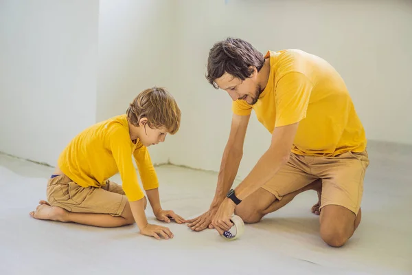 Papá e hijo están colocando aislamiento del suelo. Rollo de tela aislante para instalar un piso de madera laminado — Foto de Stock