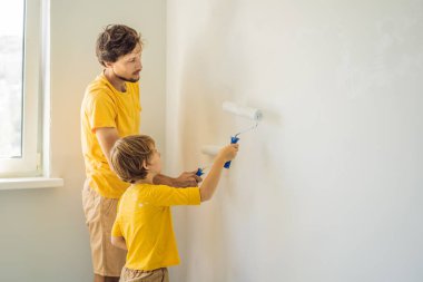 Baba ve oğul evlerinde duvar boyuyor. Taşınırken yapıyorlar.