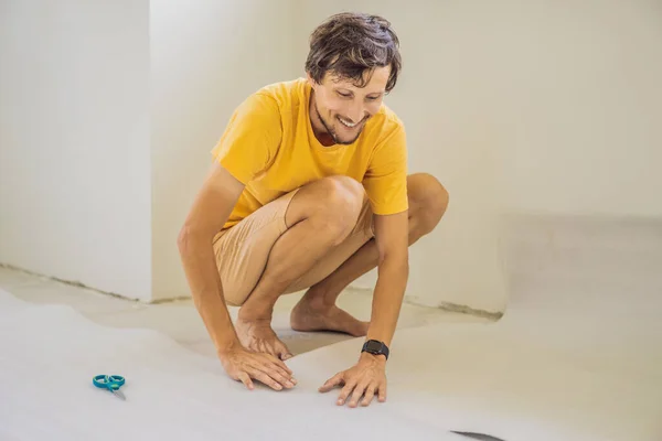 Hombre y un rollo de tela aislante para instalar un piso de madera laminado — Foto de Stock