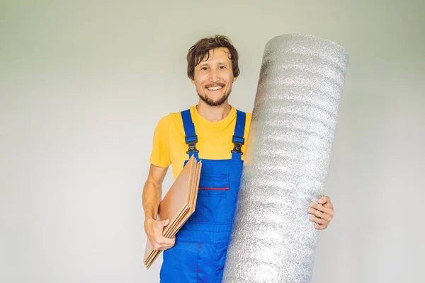 Homem segurando um rolo de pano isolante para instalar um piso de madeira laminado — Fotografia de Stock