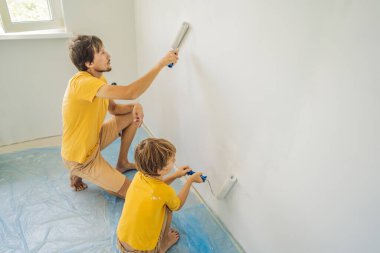 Baba ve oğul evlerinde duvar boyuyor. Taşınırken yapıyorlar.