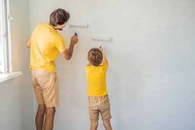 Baba ve oğul evlerinde duvar boyuyor. Taşınırken yapıyorlar.