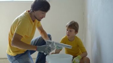 Genç bir adam ve oğlu evlerinde duvarları yeniliyorlar. Duvara macun sürüyorlar. Kendin tadilat yap. Çocuklara kendi başlarına nasıl tamir edeceklerini öğretmek.