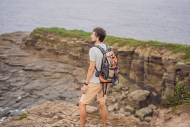 Güzel kayaların ve denizin arka planında erkek turist. Yürüyüş konsepti. Tobizin pelerini. Vladivostok, Russky adası. Japon Denizi. Primorye. Primorsky krai. Rusya 'nın doğası. Turizm ve seyahat