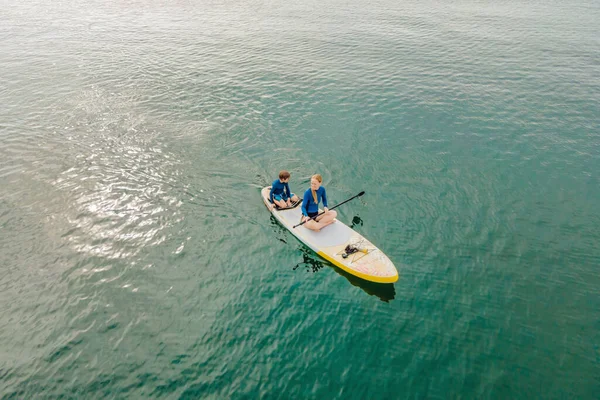 Мати і син веслують на дошці, розважаючись під час літніх канікул на пляжі — стокове фото