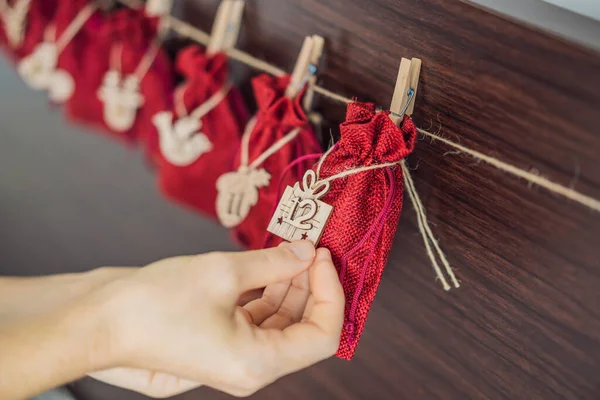 Mujer haciendo calendario de Adviento de Navidad. Bolsas en una cuerda — Foto de Stock