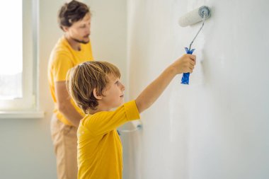 Baba ve oğul evlerinde duvar boyuyor. Taşınırken yapıyorlar.