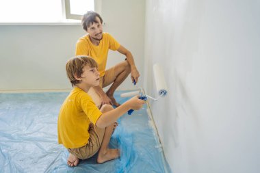 Baba ve oğul evlerinde duvar boyuyor. Taşınırken yapıyorlar.