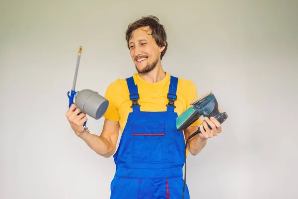 Pintor em roupas de trabalho com uma pistola de pintura — Fotografia de Stock