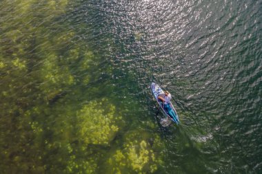 Günbatımının güzel renklerine sahip düz, sessiz bir denizde kürek çeken kişi ayağa kalksın.