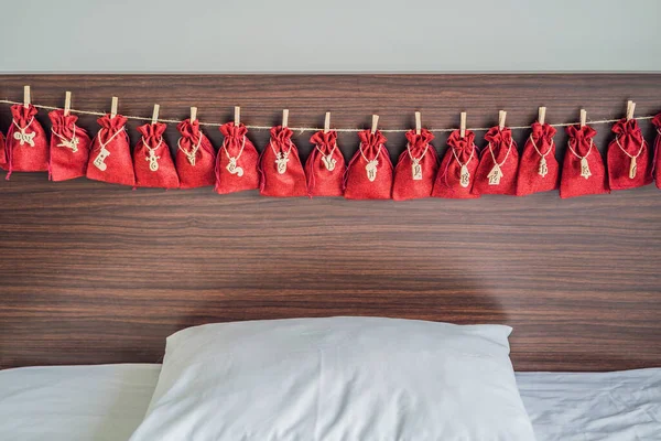 Calendario de Adviento bolsas rojas en una cuerda cuelgan de una cama infantil — Foto de Stock