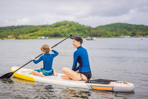 Madre e hijo remando en stand up board divirtiéndose durante las vacaciones de verano en la playa — Foto de Stock