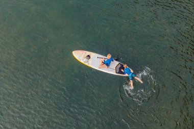 Anne ve oğul ayakta kürek çekiyorlar yaz tatilinde eğleniyorlar.