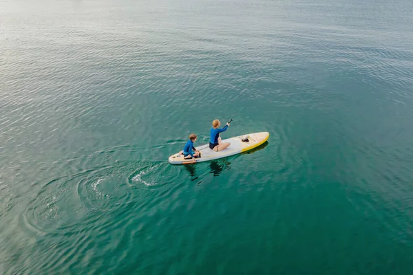 Mère et fils pagayant sur la planche debout s'amusant pendant les vacances d'été à la plage — Photo