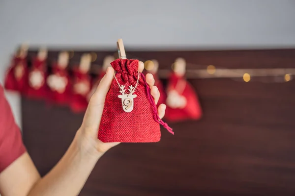 Mujer haciendo calendario de Adviento de Navidad. Bolsas en una cuerda — Foto de Stock