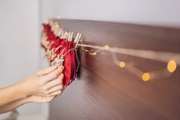 Mujer haciendo calendario de Adviento de Navidad. Bolsas en una cuerda — Foto de Stock
