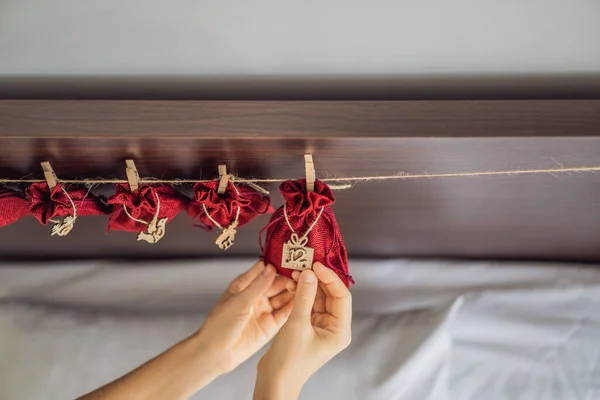 Mujer haciendo calendario de Adviento de Navidad. Bolsas en una cuerda — Foto de Stock