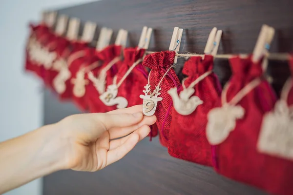 Mujer haciendo calendario de Adviento de Navidad. Bolsas en una cuerda — Foto de Stock