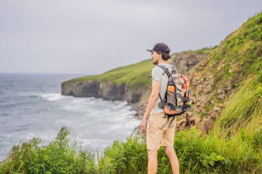 Güzel kayaların ve denizin arka planında erkek turist. Yürüyüş konsepti. Tobizin pelerini. Vladivostok, Russky adası. Japon Denizi. Primorye. Primorsky krai. Rusya 'nın doğası. Turizm ve seyahat