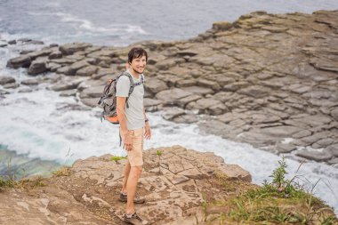Güzel kayaların ve denizin arka planında erkek turist. Yürüyüş konsepti. Tobizin pelerini. Vladivostok, Russky adası. Japon Denizi. Primorye. Primorsky krai. Rusya 'nın doğası. Turizm ve seyahat