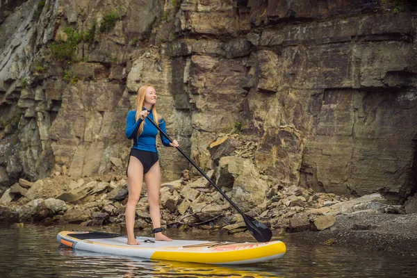 Jovens mulheres se divertindo Stand Up Paddling no mar. SUP. Menina de cabelo vermelho Treinamento em Paddle Board perto das rochas — Fotografia de Stock