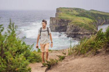 Güzel kayaların ve denizin arka planında erkek turist. Yürüyüş konsepti. Tobizin pelerini. Vladivostok, Russky adası. Japon Denizi. Primorye. Primorsky krai. Rusya 'nın doğası. Turizm ve seyahat