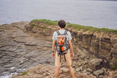 Güzel kayaların ve denizin arka planında erkek turist. Yürüyüş konsepti. Tobizin pelerini. Vladivostok, Russky adası. Japon Denizi. Primorye. Primorsky krai. Rusya 'nın doğası. Turizm ve seyahat