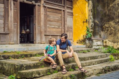 Baba ve oğul, Hoi An antik kenti, Vietnam 'ın arka planında seyahat ediyorlar. Vietnam, Coronovirus COVID 19 karantinasından sonra turistlere tekrar açıldı