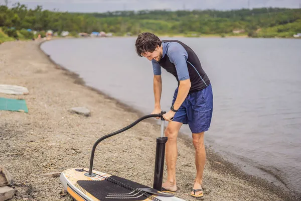 L'homme de sport gonfle la planche de pagaie de pompe, divertissement moderne à la mode — Photo