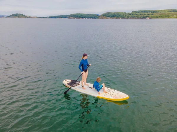 Mère et fils pagayant sur la planche debout s'amusant pendant les vacances d'été à la plage — Photo