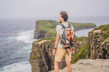 Güzel kayaların ve denizin arka planında erkek turist. Yürüyüş konsepti. Tobizin pelerini. Vladivostok, Russky adası. Japon Denizi. Primorye. Primorsky krai. Rusya 'nın doğası. Turizm ve seyahat