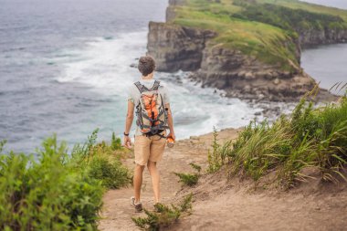 Güzel kayaların ve denizin arka planında erkek turist. Yürüyüş konsepti. Tobizin pelerini. Vladivostok, Russky adası. Japon Denizi. Primorye. Primorsky krai. Rusya 'nın doğası. Turizm ve seyahat