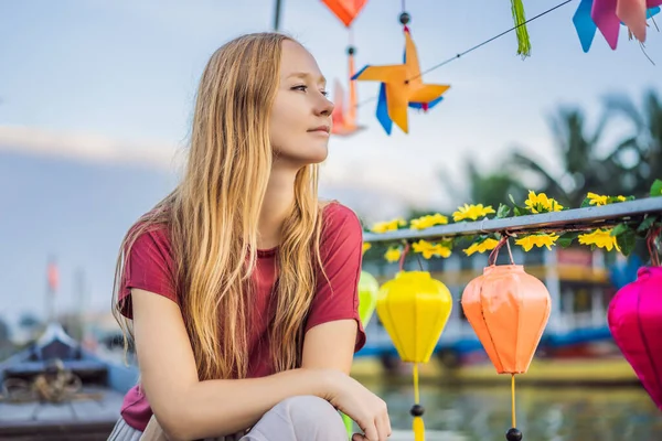Mutlu kadın gezgin, Hoi 'nin arka planında ulusal bir tekneye biniyor. Eski bir kasaba, Vietnam. Vietnam, Coronovirus COVID 19 karantinasından sonra turistlere tekrar açıldı