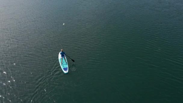 Aerial shot. Young women is having fun. Stand Up Paddling in the sea. SUP. Paddling among debrees of a sunk metal ships — Stock Video