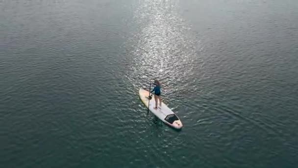 Aerial shot. Young women is having fun. Stand Up Paddling in the sea. SUP. Red hair girl Training on Paddle Board among rocks — Stock Video