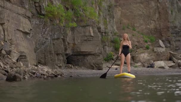 Wanita muda bersenang-senang. Berdiri mengayuh di laut. SUP. Gadis rambut merah Pelatihan Paddle Board antara batu — Stok Video