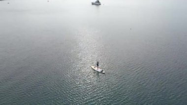 Hava görüntüsü. Genç kadınlar eğleniyor. Denizde kürek çekerek ayağa kalk. - Süper. Kızıl saçlı kız kayaların arasında kürek çekiyor.
