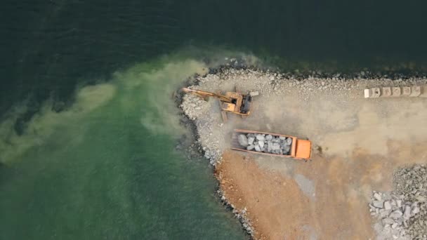 Flygvideo. Utsikt från bob och grävmaskin som arbetar med att bygga ett land i ett hav. Fylla stranden med en sten. Kustlinje Stärkande, Erosion Control, Bekämpa havsnivån stiger. Kustnära — Stockvideo