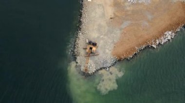 Hava videosu. Denizde bir kara parçası inşa etmeye çalışan gemi ve kazıcının görüntüsü. Kıyıyı bir taşla dolduruyor. Kıyı şeridi güçlenmesi, erozyon kontrolü, okyanus seviyesi yükselmesiyle mücadele. Kıyı