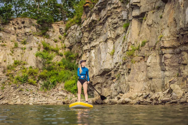 Giovani donne che si divertono Stand Up Paddling nel mare. SUP. Rosso capelli ragazza Formazione su Paddle Board vicino alle rocce — Foto Stock
