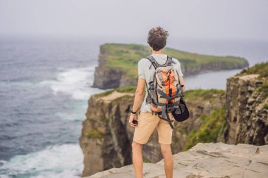 Güzel kayaların ve denizin arka planında erkek turist. Yürüyüş konsepti. Tobizin pelerini. Vladivostok, Russky adası. Japon Denizi. Primorye. Primorsky krai. Rusya 'nın doğası. Turizm ve seyahat