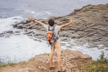 Güzel kayaların ve denizin arka planında erkek turist. Yürüyüş konsepti. Tobizin pelerini. Vladivostok, Russky adası. Japon Denizi. Primorye. Primorsky krai. Rusya 'nın doğası. Turizm ve seyahat