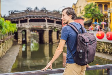 Hoi An 'daki Güzel Japon Köprüsü' nün arka planındaki erkek turist. Vietnam. Vietnam, Coronovirus COVID 19 karantinasından sonra turistlere tekrar açıldı