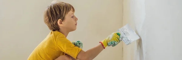 L'uomo con suo figlio fa riparazioni a casa, insegna ai bambini a intonacare le pareti con una spatola in mano BANNER, FORMATO LUNGO — Foto Stock